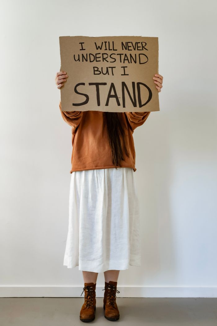 Woman in brown boots holding sign in indoor studio.